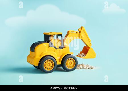Das gelbe Mini-Bagger-Spielzeug trägt Steinschutt Stockfoto