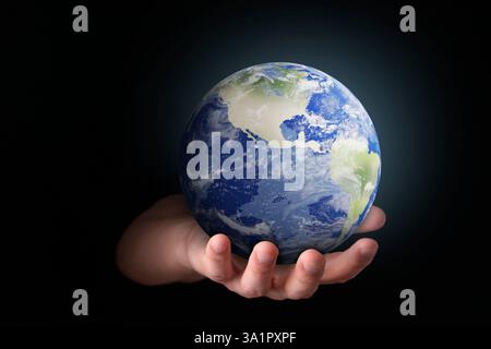 Planet in unseren Händen. Mann, der das Erdmodell auf schwarzem Hintergrund hält, Nahaufnahme Stockfoto