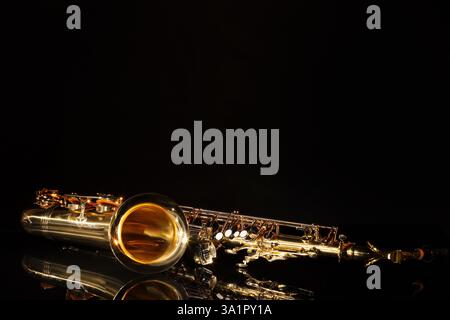 Jazz. Ein Saxophon auf Spiegelfläche vor schwarzem Hintergrund, Platz für Text Stockfoto