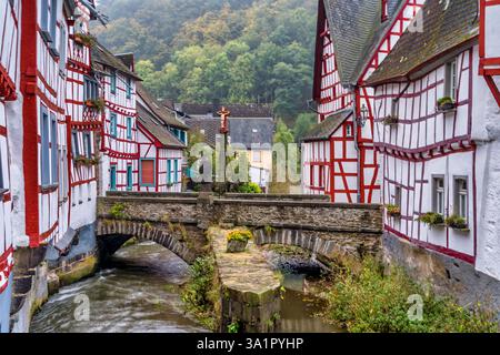 Mittelalterliche rote Fachwerkhäuser im Monreal Deutschland mit Brücke über dem Elzbach mit Kruzifix Stockfoto