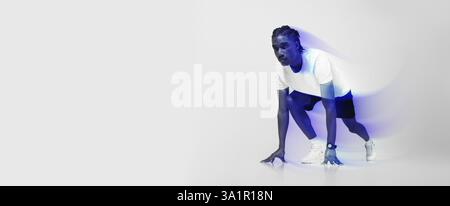 Fokussierter Mann in sportlicher Kleidung, bereit in Startposition für Sprint Stockfoto