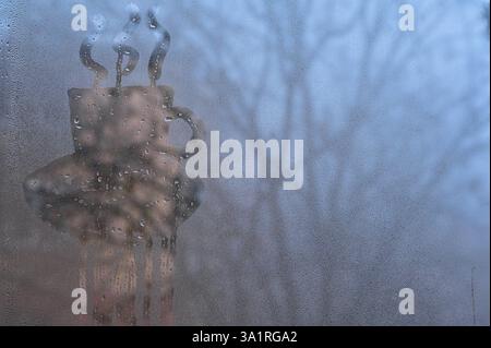 Bemalte Kaffeetassen auf einem nassen Fenster. Das Konzept Stockfoto