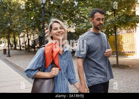 Glückliches Paar, das Hand in Hand durch den Park geht Stockfoto