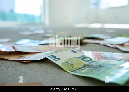 Euro-Banknoten, die auf Betonböden in einer neuen unvollendeten Wohnung verstreut sind, symbolisieren die Finanzplanung. Konzept von Investition, Budgetierung und Immobilien Stockfoto