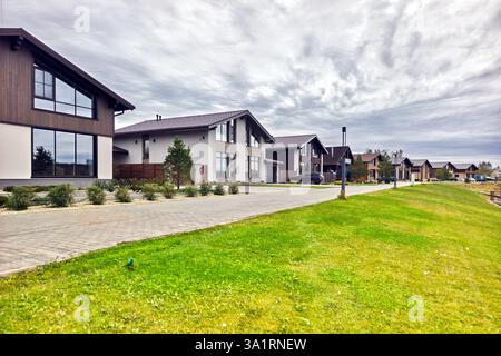 Modernes neues Landhaus mit großem Rasen. Häuser in den Vororten im Sommer, sonnig. Luxuriöses Landhaus. Eine Straße mit neuen zweistöckigen Häusern mit Mod Stockfoto