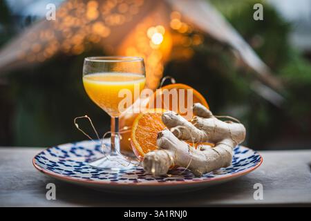 Ingwerschuss mit frischen Orangen und Ingwerwurzel auf rustikalem Tisch Stockfoto