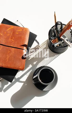 Bücherstapel und Tasse Espresso auf weißem Schreibtisch. Stockfoto