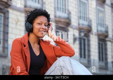 Junge Frau, die Musik mit Kopfhörern in urbaner Umgebung genießt Stockfoto