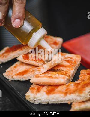 Olivenöl über geröstete Brotscheiben gießen. Selektiver Fokus. Stockfoto