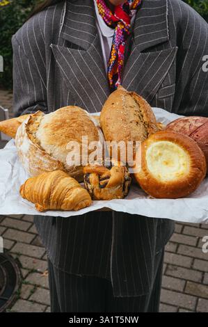 Frisches Gebäck und Brot auf einem Tablett in den Händen Stockfoto