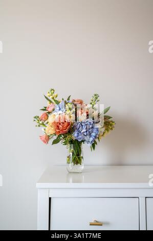 Bunter Blumenstrauß im Glasgefäß auf dem Schrank Stockfoto
