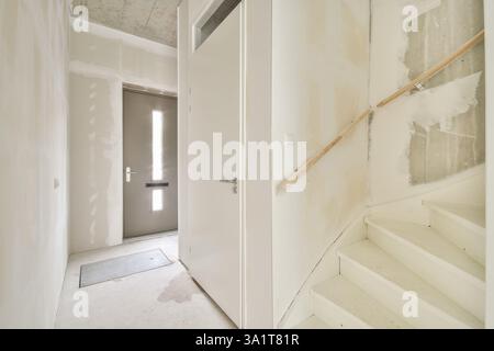Ein elegantes, modernes Interieur mit einer weißen Treppe und einem modernen Türdesign vor minimalistischen Wänden. Der Raum ist hell und einladend. Stockfoto