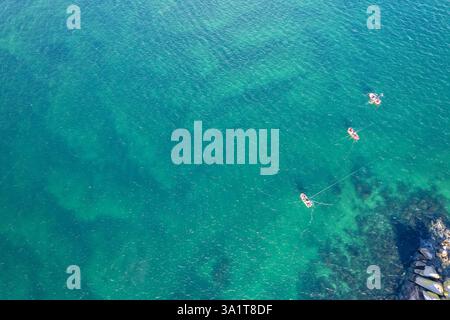 Kleine Fischerboote, die in einem türkisfarbenen Meerwasser am Ufer schwimmen, zenithaler Blick von einer Drohne Stockfoto
