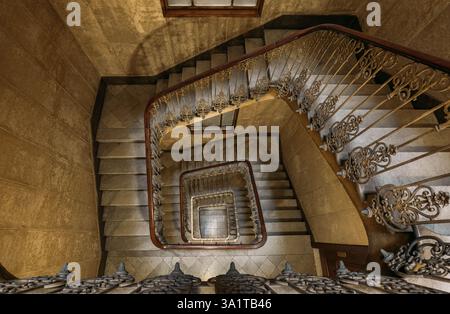 Vintage Wendeltreppe mit kunstvoll verziertem Eisengeländer und hölzernem Handlauf Stockfoto