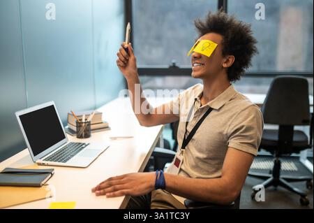 Mann mit gelben Notizen im Gesicht, der Spaß im Büro hat Stockfoto