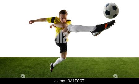 Seitenansicht eines fokussierten jungen Mannes, eines Fußballspielers, der akrobatische Hochtritte durchführt, das Bein in Richtung Ball hebt und intensiv vor weißem Hintergrund fokussiert. Stockfoto