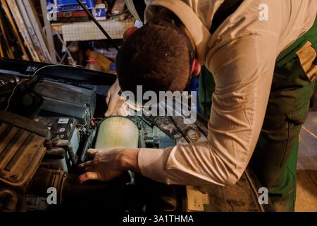 Professioneller Automechaniker, der den Luftfilter in der Werkstatt überprüft und repariert. Stockfoto
