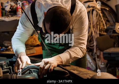 Nahaufnahme eines Mechanikers, der Motorkomponenten in Werkstatteinstellung sorgfältig inspiziert und repariert. Stockfoto