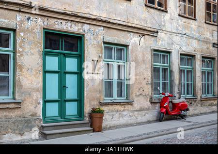 Ein roter Oldtimer auf einem Fußgängerweg vor einem alten Steinhaus Stockfoto