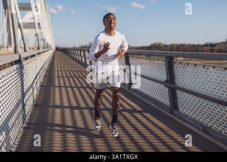 Der junge afroamerikanische Mann joggt auf der Brücke in der Stadt. Stockfoto