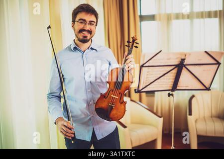 Porträt eines Mannes mit Geige zu Hause. Er übt für Live-Auftritte. Stockfoto