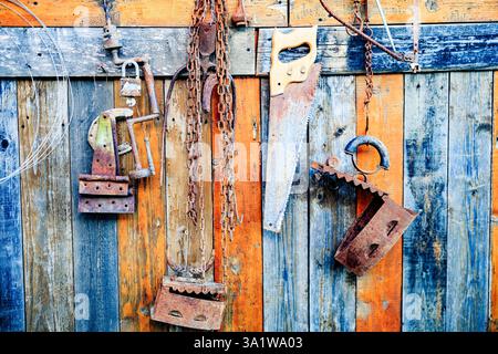 Alte alte rostige Haushaltswerkzeuge auf bunten Holzbrett Hintergrund. Stockfoto