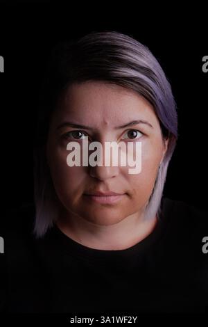 Studio-Porträt einer 40-jährigen Frau vor schwarzem Hintergrund. Stockfoto