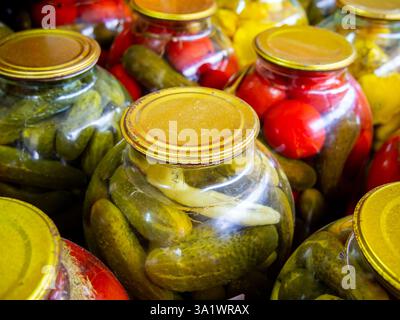 Glasreihen mit hausgemachten eingelegten Gurken und Tomaten Stockfoto