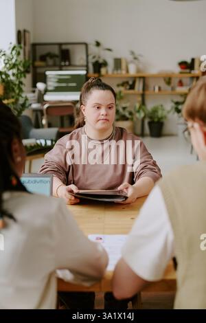 Vertikalaufnahme einer jungen kaukasischen Kandidatin beim Vorstellungsgespräch im gemütlichen Büro Stockfoto