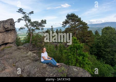 Frau sitzt auf einem Felsen mit Blick auf die Berge. Wandern in den Bergen und Alleinreisen. Erholung und Entspannung. Mocap. Hochwertige Fotos Stockfoto
