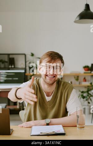 Vertikales Porträt eines glücklichen einstellenden Managers, der beim Sitzen am Schreibtisch im Büro zur Seite steht Stockfoto