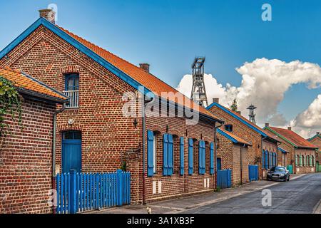 Rote Backsteinhäuser mit blauen Fensterläden am Arenberg-Bergbaugelände unter blauem, bewölktem Himmel. Nord-Pas-de-Calais, Wallers, Frankreich, Europa Stockfoto