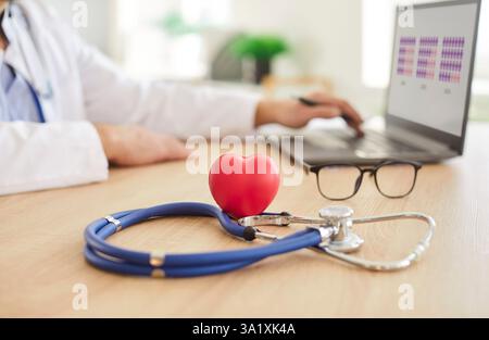 Professionelles Stethoskop-Untersuchungsgerät für Kardiologen, rotes Herzsymbol auf dem Schreibtisch Stockfoto