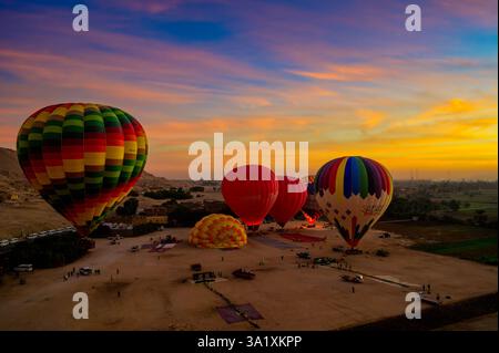 Aufgeblasene und halbaufgeblasene Heißluftballons bereiten sich auf den Start für die Fahrt im Heißluftballon am frühen Morgen bei Sonnenaufgang über das Land der alten Pharaonen vor Stockfoto