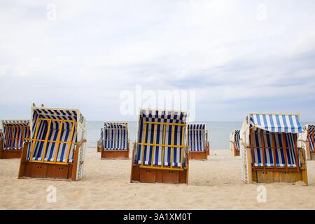 Am weitläufigen Sandstrand von Kolobrzeg sorgen Vintage-Holz und Korbkörbe mit weiß-blauen Streifen für Schatten für Strandgänger. Die ruhige Ostsee Stockfoto
