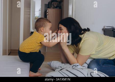 Mutter und Baby spielen zusammen mit Entwicklungsspielzeug, sitzen auf dem Boden, fördern das Lernen. Hochwertige Fotos Stockfoto