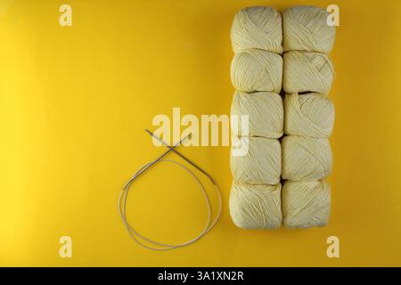 Auf gelbem Hintergrund befindet sich gelbes Garn zum Stricken und Stricken von Nadeln. Geschäftskonzept Stockfoto