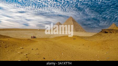 Touristen reiten Kamele in Richtung der Pyramide von Khafre auf dem Gizeh-Plateau in Ägypten Stockfoto