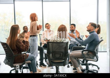 Die junge Frau steht und redet über sich selbst. Eine Gruppe von Menschen trifft sich zusammen mit einer Therapie. Stockfoto
