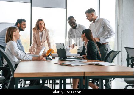 Bei der Besprechung über die Pläne. Eine Gruppe von Büroangestellten ist drinnen zusammen. Stockfoto