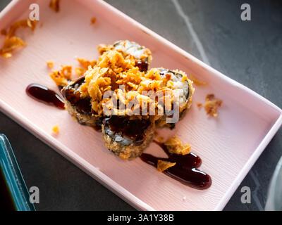 Frittierte Sushi-Brötchen mit knusprigen Zwiebeln und Teriyaki-Sauce Stockfoto