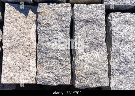 Graue Granitsteine, 6 cm dick, 15 cm lang, stehen nebeneinander, beleuchtet von hellem Sonnenlicht, Nahaufnahme. Hochwertige Fotos Stockfoto