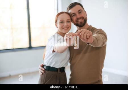 Glückliches Paar als neue Besitzer des Hauses, die Schlüssel in der Hand halten. Stockfoto
