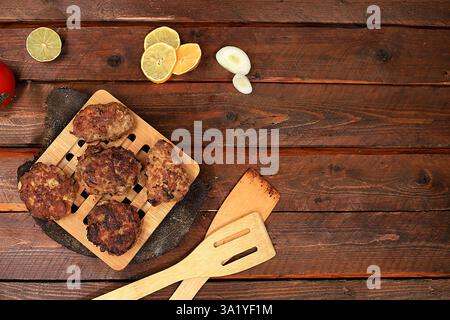 Hausgemachte Schnitzel mit Zwiebeln, Tomaten und Knoblauch, scharfe Kräuter auf hölzernem Hintergrund, köstliche natürliche Speisen, Werbung für das Menü, Café Restaura Stockfoto