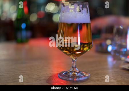 Goldenes Bier in elegantem Glas auf Holzbar Stockfoto