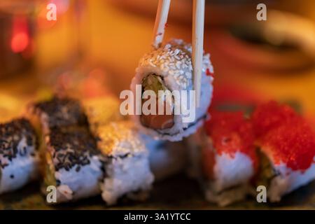 Nahaufnahme von Rainbow Roll Sushi mit Stäbchen Stockfoto