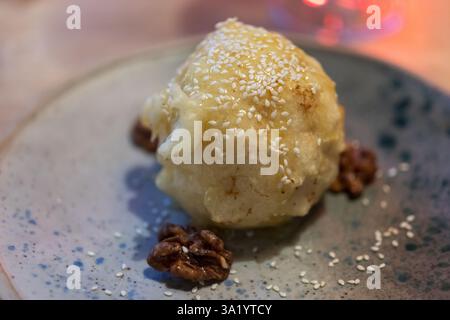 Köstliches japanisches frittiertes Eis, Golden und knusprig, mit Honig getränkt und mit Sesamsamen bestreut. Das Dessert wird auf einem stilvollen Teller serviert Stockfoto