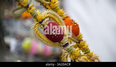 Festliche Osterdekoration mit farbenfrohen, strukturierten Eiern und natürlichen Strohakzenten, die eine bezaubernde, handgefertigte saisonale Präsentation schaffen. Stockfoto