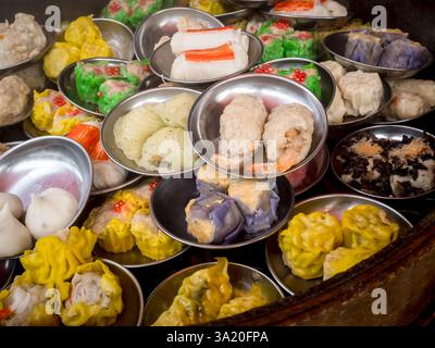 Verschiedene traditionelle Gerichte chinesisches Dim Sum in Minischüsseln im Dampfgarer, zubereitet in einem lokalen Restaurant. Nahaufnahme chinesisches Dim Sum Take-away Fingerfood. Lecker Stockfoto