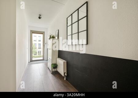 Ein eleganter und stilvoller Flur mit einer Mischung aus hellen und dunklen Wänden, einem Schrank und einem großen Spiegel. Ideal für moderne, minimalistische Einrichtung. Stockfoto